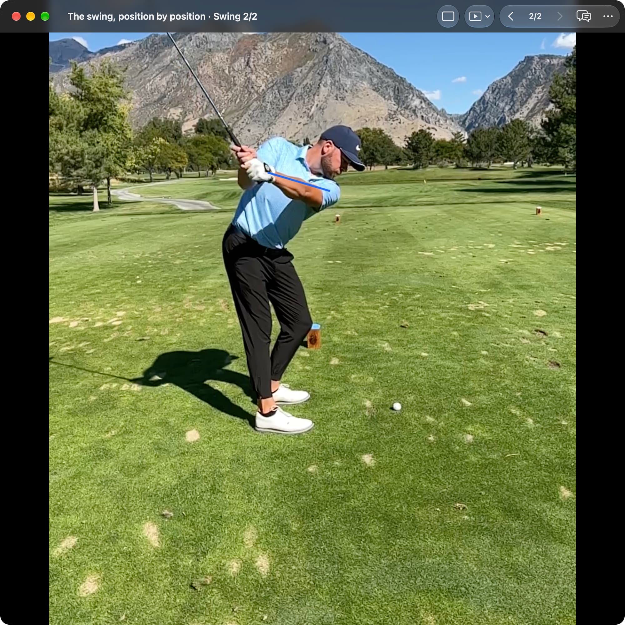 A golfer in MotionEdge Video Player, down-the-line on a course, in the backswing. A blue line follows the lead arm across the chest while the shaft points upward at a different angle.