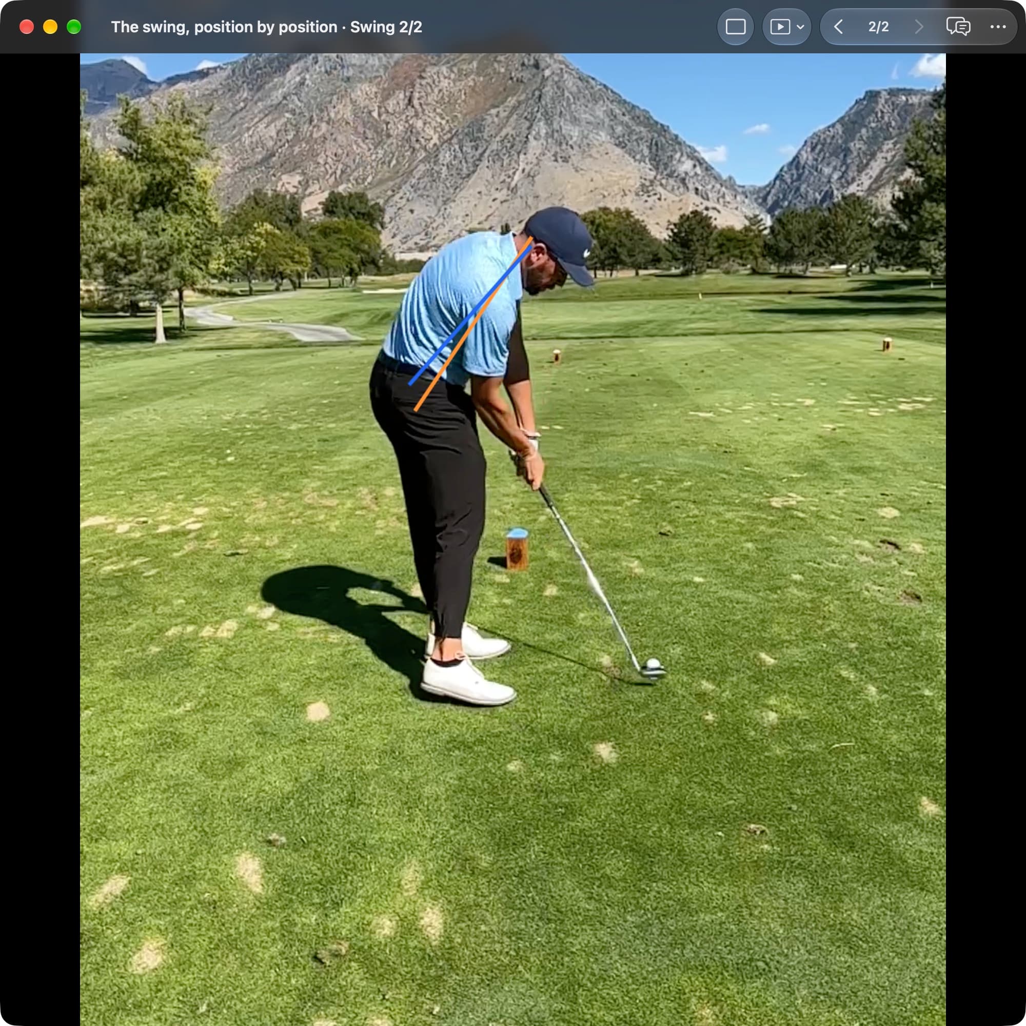 A golfer at impact in MotionEdge Video Player, down-the-line, recorded at a high frame rate. The clubhead is at the ball. An orange line shows the torso angle from Address and a blue line shows it in this frame, slightly more upright.