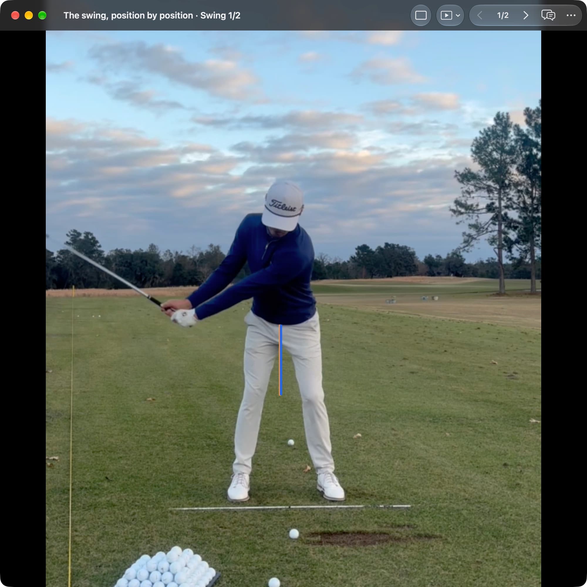 A golfer in MotionEdge Video Player, face-on on a range, early in the takeaway with the club about waist high. An orange line marks the pelvis center at Address and a blue line marks it now, almost on top of it.
